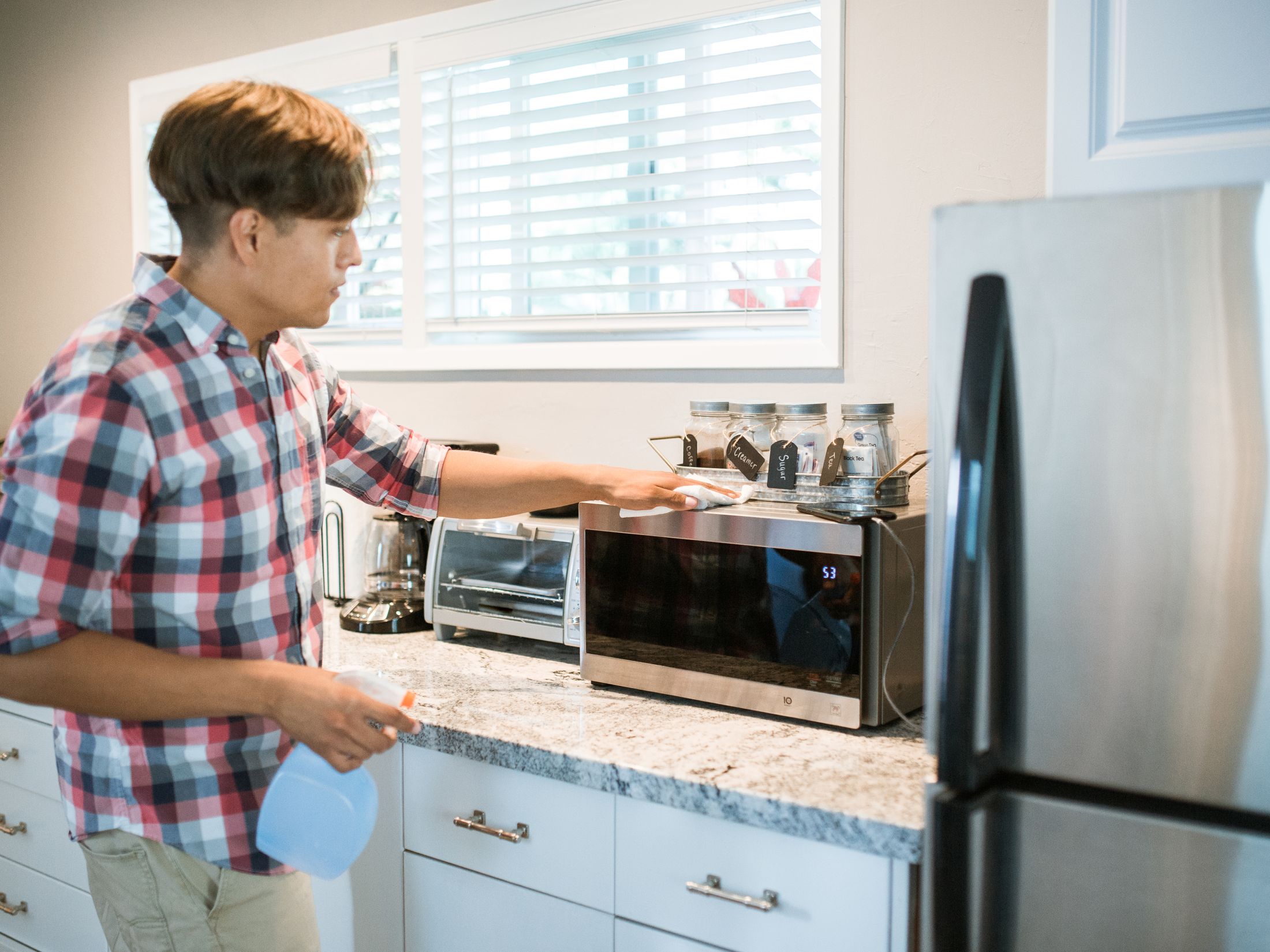 Cleaning a kitchen appliance with a spray bottle and cloth